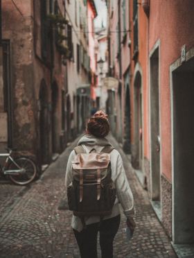Chica con una mochila andando por una calle estrecha